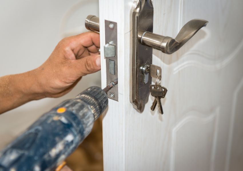 person using a drill to secure a doors locking system